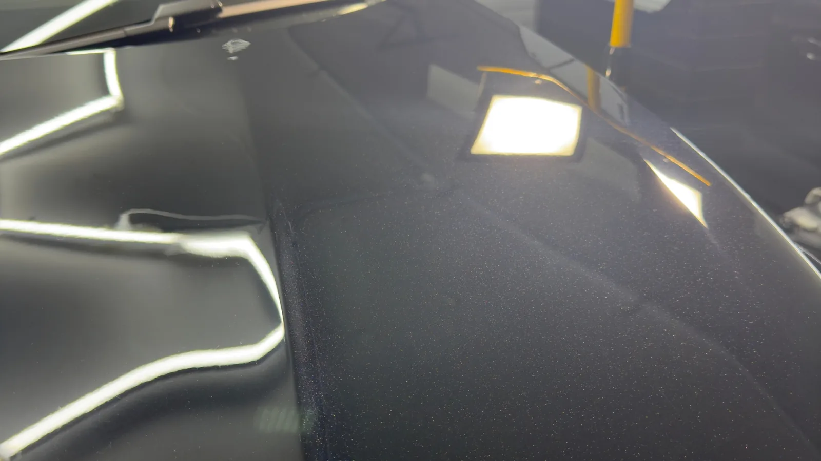 Polished black car bonnet under LED lights in a Baulkham Hills ceramic coating studio